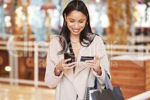 No better feeling than saving money. a young woman using her smartphone to make an online payment using her credit card.