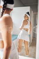 Keeping it cute on the court. an attractive young woman checking herself in the mirror in the locker room at a tennis arena.