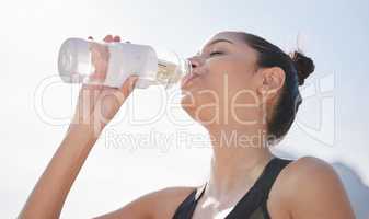 Drink more water, your body will thank you for it. a young woman drinking water after working out in nature.