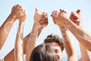 Lift them up high. a group of unrecognizable people holding hands outside.