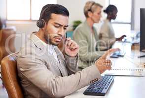Hold on some information is coming through. a young businessman working in a call center.