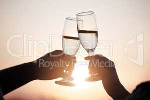 Heres to happy ever afters. a young couple making a toast while on a picnic at sunset.