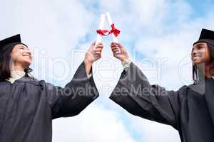 Take charge of your future. Low angle shot of two young women celebrating with their diplomas on graduation day.