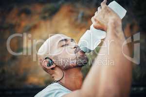 Exercise is the safest way to health. a sporty young man drinking water while exercising outdoors.