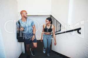 Im glad that we get to train together. a sporty young man and woman walking up a staircase together.