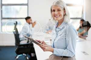 Making sure shes updated with her digital calendar. Portrait of a confident mature businesswoman using a digital tablet in an office.