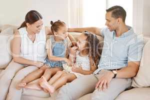 Theres no place better in the world than home. a couple and their two daughters sitting on the couch at home.