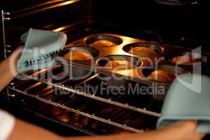 Teach them how to survive on their own. an unrecognizable little girl baking muffins in the oven at home.