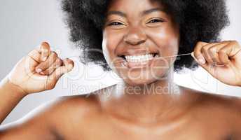 Wake up, wash up, floss up. Studio shot of an attractive young woman flossing her teeth against a grey background.