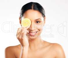 Citrus is good for the skin. Studio portrait of an attractive young woman posing with a slice of lemon against a grey background.