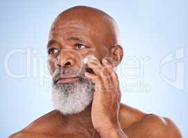 The markings on rejuvenation. Studio shot of a mature man applying moisturiser to his face against a blue background.