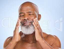 Oh, sweet textures. Studio shot of a mature man applying moisturiser to his face against a blue background.