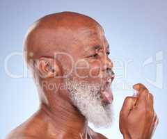 Quick fixes and busy lives. Studio shot of a mature man checking his breath and using breath freshening spray against a blue background.