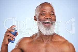 This fragrance takes me back. Studio portrait of a mature man spraying himself with aftershave against a blue background.