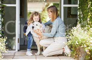 Mommy, let me hold him. a mother and daughter bonding with their dog in the backyard at home.