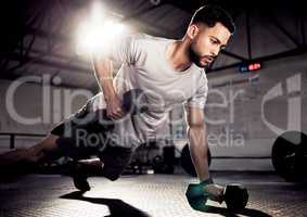 Motivation determines what you do. a muscular young man exercising with a dumbbell in a gym.