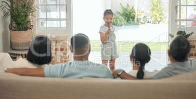 Showing my family my music act. an adorable little girl standing in the living room at home and singing for her family.