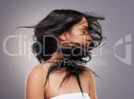 To add volume, shake your hair. an attractive young woman standing alone in the studio and flipping her hair.