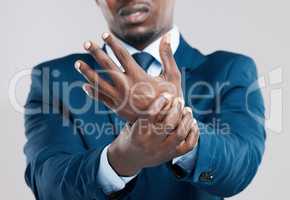 The aches and pains of persistent use. Studio shot of a businessman experiencing wrist tension against a grey background.