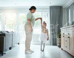 She wants to be a little ballerina. a little girl wearing her tutu while dancing with her mother at home.