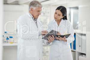 Working with her supervisor to solve the case. two scientists using a digital tablet together in a lab.