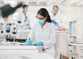 I have a full schedule of discoveries to make today. a young scientist writing notes while working in a lab.
