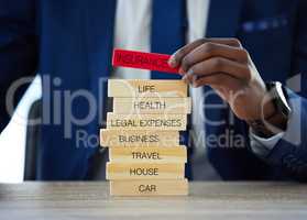Its worth it to insure it. an unrecognisable businessman assembling wooden blocks with insurance related words on them.