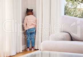 Shes been sent to timeout. a little girl standing in the corner as a punishment at home.