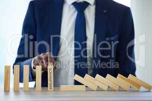 It can happen faster than you think. an unrecognisable businessman working with falling wooden blocks that have the word insurance on them.
