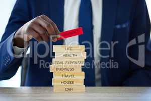 Life happens, insurance helps. an unrecognisable businessman assembling wooden blocks with insurance related words on them.