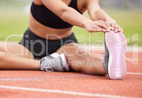 The final stretch. an unrecognizable female athlete going through her warmups out on the track.