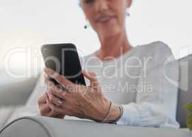 Its easy to stay connected. an unrecognizable senior woman sending a text while relaxing in her living room at home.