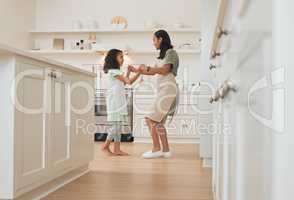 Twisting the day away. a mother and daughter dancing around the kitchen while baking.