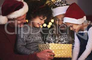 Family is the greatest gift of all. a family opening a Chrstmas gift together at home.