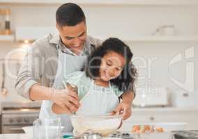 Remember to scrape the sides of the bowl. a young father helping his daughter bake.