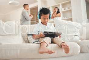 Youve failed your family. a little boy wearing a headset and using a digital tablet while his parents argue in the background at home.