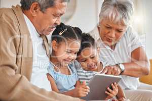 Blessed to be loved. grandparents bonding with their grandchildren and using a digital tablet on a sofa at home.
