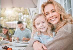 A family is one of natures solubles. a mother hugging her daughter at a family lunch at home.