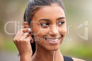 Pleasant memories brings broad smiles. a young woman listening to music while jogging.