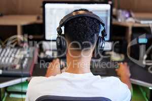 Producing another banger. Rearview shot of an unrecognizable male music producer working on his mix in the office.