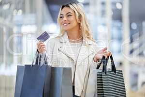 Its a wonderful day for some spoils. a young woman holding the bank card used to make payments while shopping.