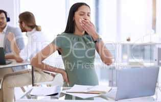 I cant continue working when Im this tired. a young pregnant businesswoman sitting in her office and yawning.