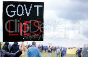 We will no longer fall for your lies. Unrecognisable demonstrators holding up signs and protesting against government corruption.