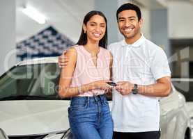 Dont just dream about it, drive it. a young couple showing their car keys at a car dealership.