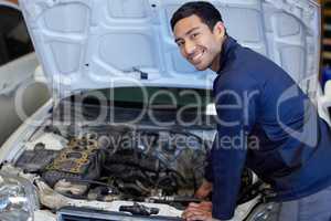 Everything looks good. High angle portrait of a handsome young male mechanic working on the engine of a car during a service.