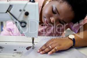 Sewing is precise work. an attractive young seamstress using a sewing machine while working in her boutique.