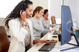 Ill sing you up right away. a young call centre agent working on a computer in an office with her colleagues in the background.