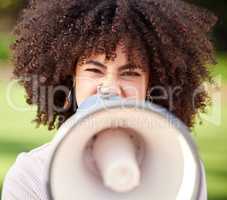 Silence becomes cowardice. a young woman screaming into a loudspeaker while protesting in the park.