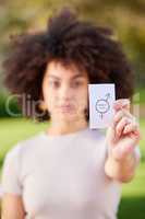 The purpose of protest to provoke a response. a young woman holding a card in protest in a park.