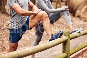 The run up to the race. an unrecognisable couple stretching before their workout in nature.